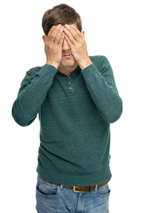 Young handsome tall slim white man with brown hair covering his eyes in dark green sweater in blue jeans isolated on white background