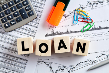 The word loan on wooden cubes with office desktop. Business and finance loan budget analysis