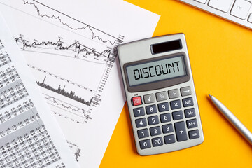 The word discount on calculator display screen with business office desktop. Calculating discounts