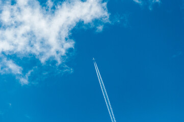 an airliner leaving a jet trail flies into the clouds in a clear blue sky.