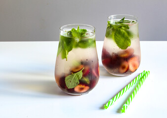 Cold drinks in small bottles. Cherries and mint lemonade. Mojito coctail. Summer iced refreshment drink. Summer cold mint coctails with berries. Mason jar glass with cold drink.