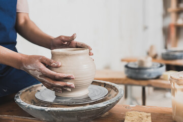 partial view of young african american woman modeling wet clay pot on wheel in pottery