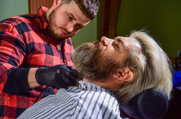 Shaving with fun. master barber does the hairstyle and styling with dryer. Concept Barbershop....