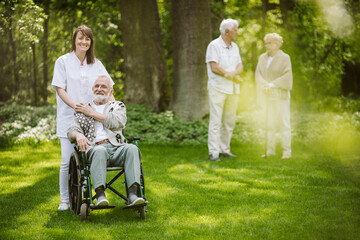 Smiling caregiver with disabled man in the garden