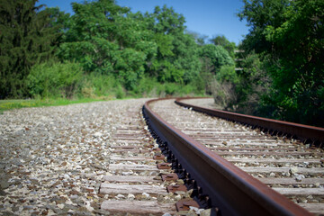 Fototapeta na wymiar Close up of rail train track with green trees and bright blue clear sky 