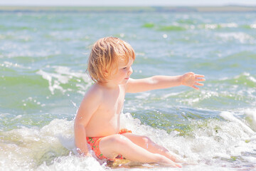 Fototapeta na wymiar cute little boy playing in sea water. the concept of childhood and summer vacations.