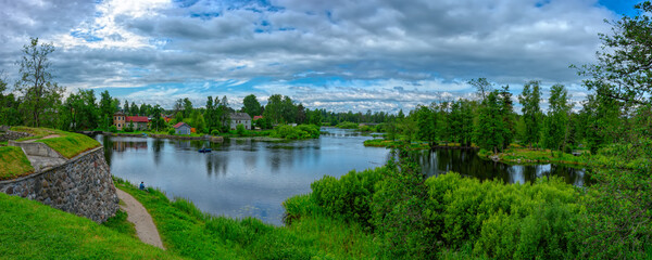Panorama of the banks of sleepy Vuoksa River at sunny summer day. Priozersk, Russia.