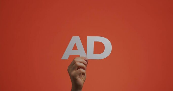 Hand raising up showing word ad. Man shows advertising sign made of carved paper for blog screen saver