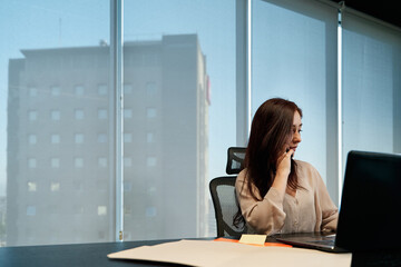 young latina business woman talking on the phone and using her laptop to work in the office, technology concept