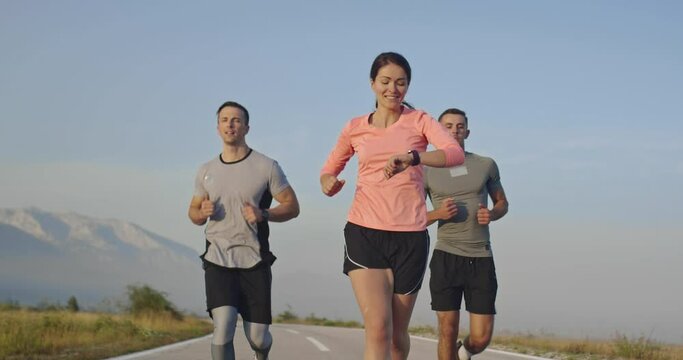 Multiethnic group of athletes running together on a panoramic road. 