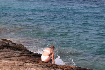 Ragazza in costume bianco sulla spiaggia di Erotospilia