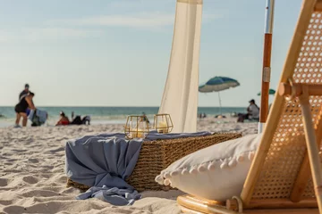 Poster Strandstoel met kussen, kaarsen en een rieten krat en parasols en de horizon op de achtergrond © Ray Dukin