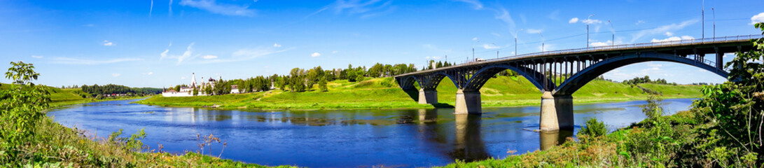 Arch bridge over the river on sunny day. Summer landscape panorama. Russia, Staritsa.