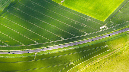 Aerial view of country road in a middle of the green farm fields in a late spring, Long Furlong, West Sussex, UK.