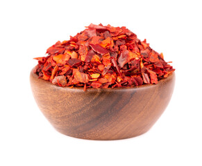 Dried red chili flakes in wooden bowl, isolated on white background. Chopped chilli cayenne pepper. Spices and herbs.