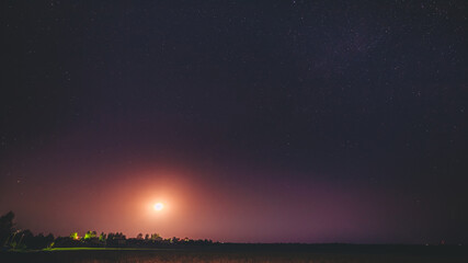 Moonrise Above Belarusian Village In Eastern Europe. Belarusian Countryside In Summer Starry Night