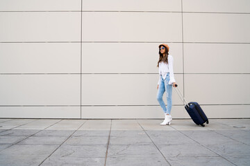 Young woman carrying a suitcase outdoors.