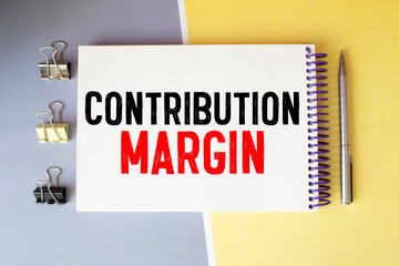 Text CONTRIBUTION MARGIN on Notebook and office tools on the gray desktop