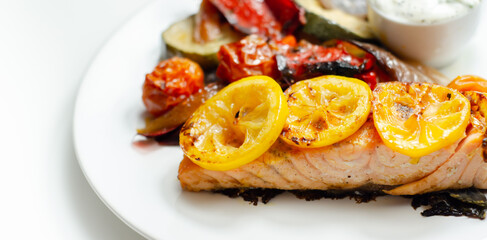 Grilled salmon fillet served with roasted vegetables with cucumber and dill sauce
