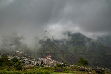 A small village at the top of Ibb mountains in Yemen. with a cloud