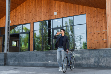 Muslim businessman drinking coffee near bicycle outdoors