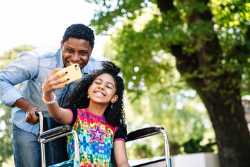 Girl in a wheelchair and her father taking a selfie with phone.