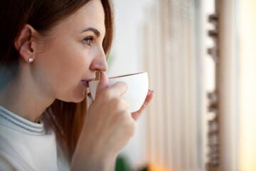 Happy young woman holding with hands a cup of healthy hot coffee latte