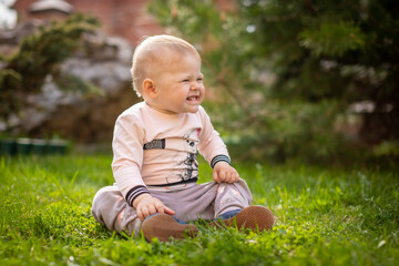 Sweet baby girl playing on green grass in park in spring time