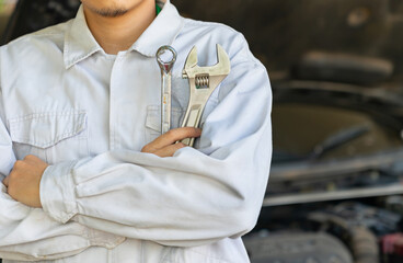 Cropped shot of auto mechanic with wrench in hands at mechanic shop.