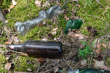 Garbage in the forest. Glass and plastic bottles thrown in the woods. The problem of environmental pollution.
