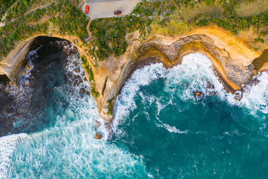 Aerial view of waves crashing below rugged see cliffs