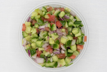 Overhead view of mediterranean salad full of chopped tomatoes, cucumbers, onions, and olive oil for a great meal on the go