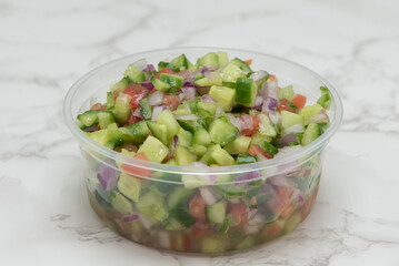 Mediterranean cuisine prepared for a meal in the form of a delicious chopped vegetable salad drizzled with olive oil.
