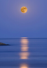 Fototapeta na wymiar Full moon over the sea with reflections in the water