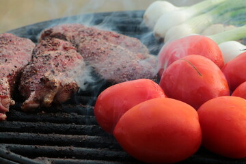 grilling some steak, onions and tomatoes on the grill