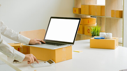 Start small business, business woman, successful SME entrepreneur. Work-at-home woman with laptop taking orders from customers with online parcel delivery. SME delivery concept and packaging