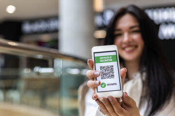 Portrait smiling woman posing with vaccine certificate on smartphone screen. Coronavirus prevention