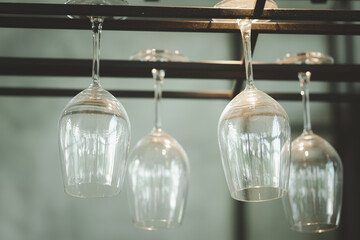 Empty glass wine glasses on a rack above the counter bar.