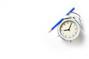 Retro alarm clock and blue pencil on white table background, vintage style