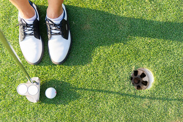 Obraz premium close up of putter hitting golf ball to hole at course.top view Golfer