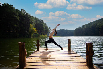 Fototapeta na wymiar Young healthy woman practicing yoga on the bridge in the nature