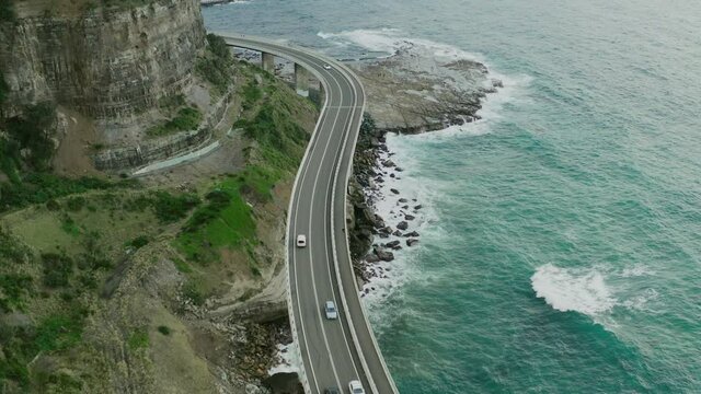Aerial footage of cars travelling on the Seacliff Bridge. 