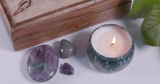Closeup of healing crystals and a candle by a wicca box