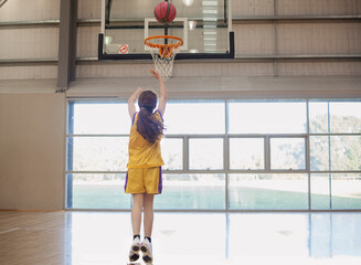 girl shooting basketball hoop.