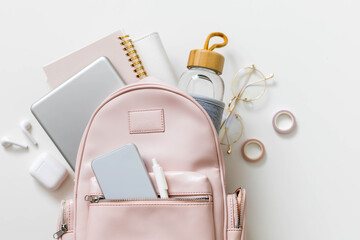 Top view elegant pink student backpack full of supplies isolated. Back to school concept