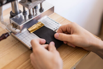 Male tanner stamping stuff use awl and machine device working at leather workshop. Handmade work