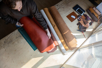 Craftsman unwrapping bundle of stuff natural material working at leather workshop. Leatherwork - Powered by Adobe