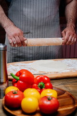 hands roll the dough into a thin layer. Cooking pizza, noodles or pitta at home