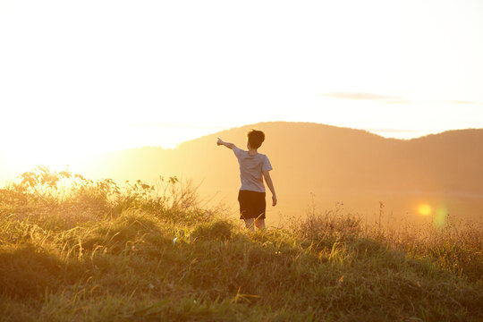 Young boy looking out to mountains at sunset