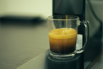 the glass of coffee made by coffee machine.
